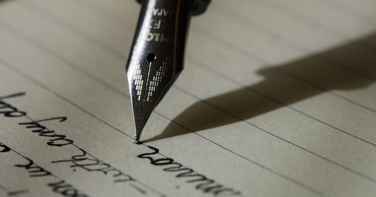 Notebook and pen on a wooden desk with warm lighting